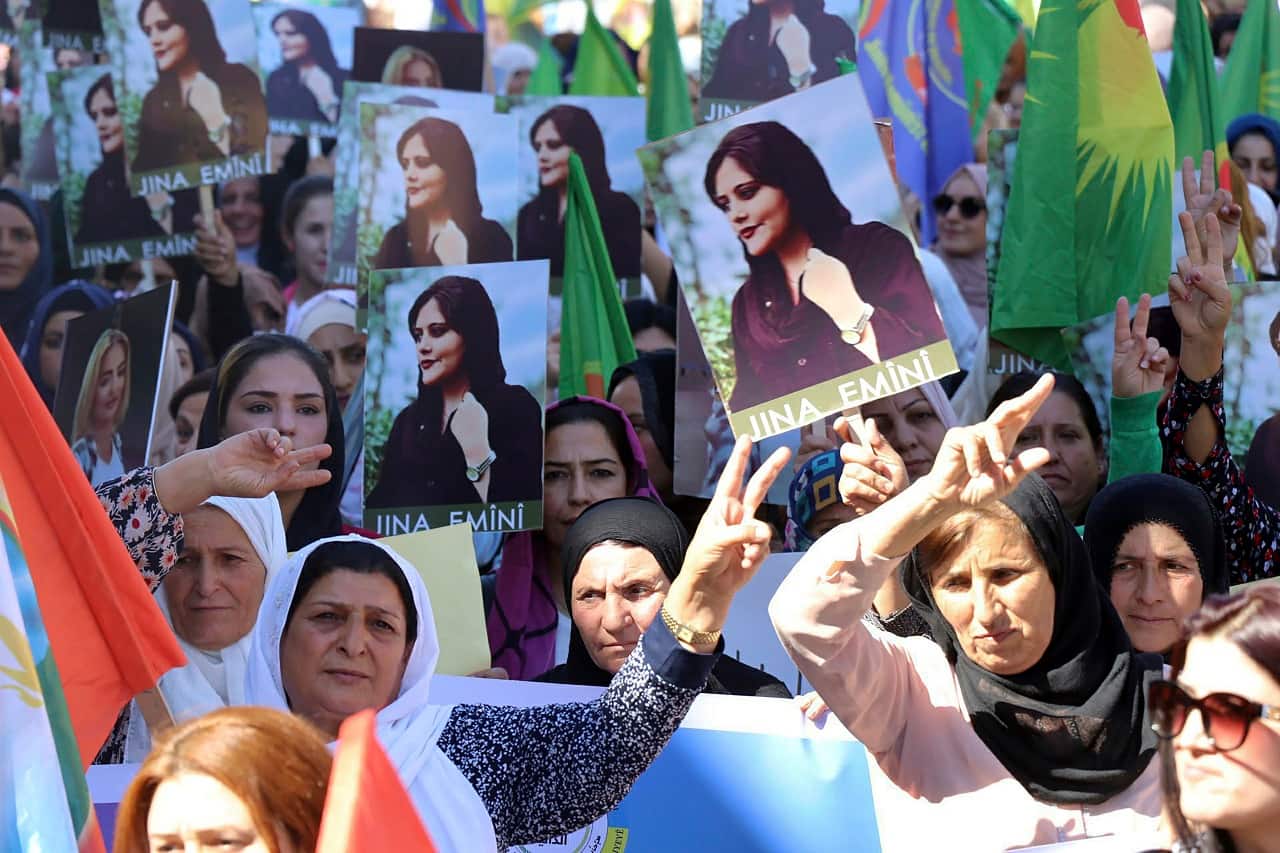 In this photo provided by Kurdish-run Hawar News Agency, Kurdish women hold portraits of Iranian Mahsa Amini, during a protest condemning her death in Iran, in the city of Qamishli, northern Syria, on Sept. 26 (Image: Hawar News Agency via AP)