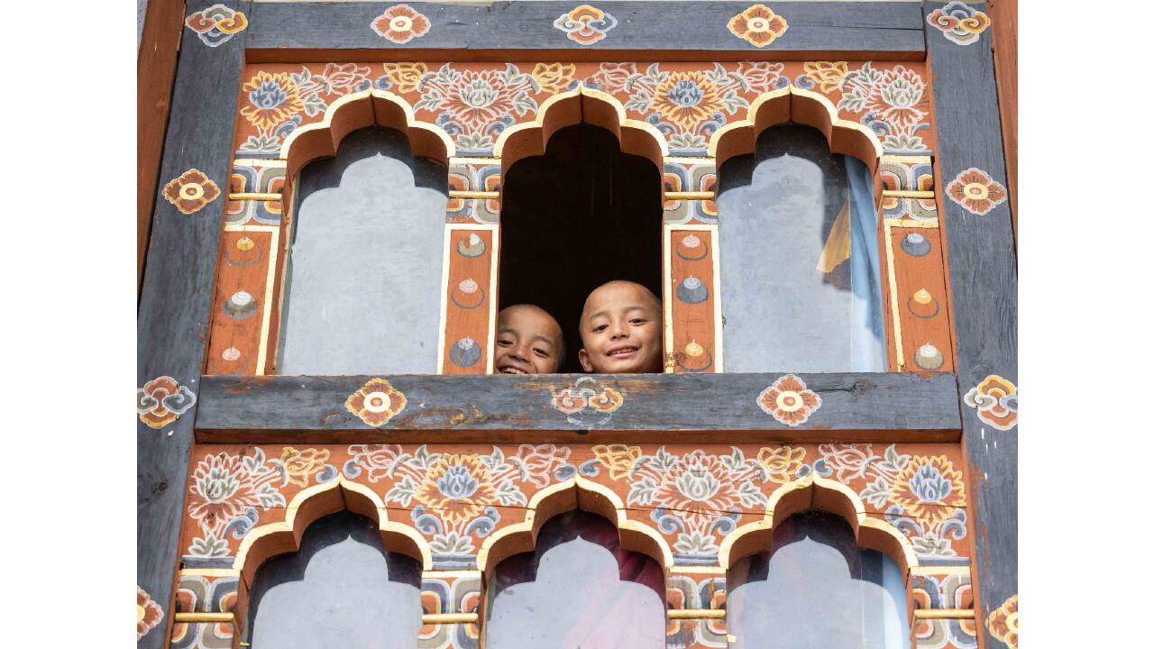 Young monks peering down from the window of a monastery along the Trans Bhutan Trail. (Photo by Ken Spence)