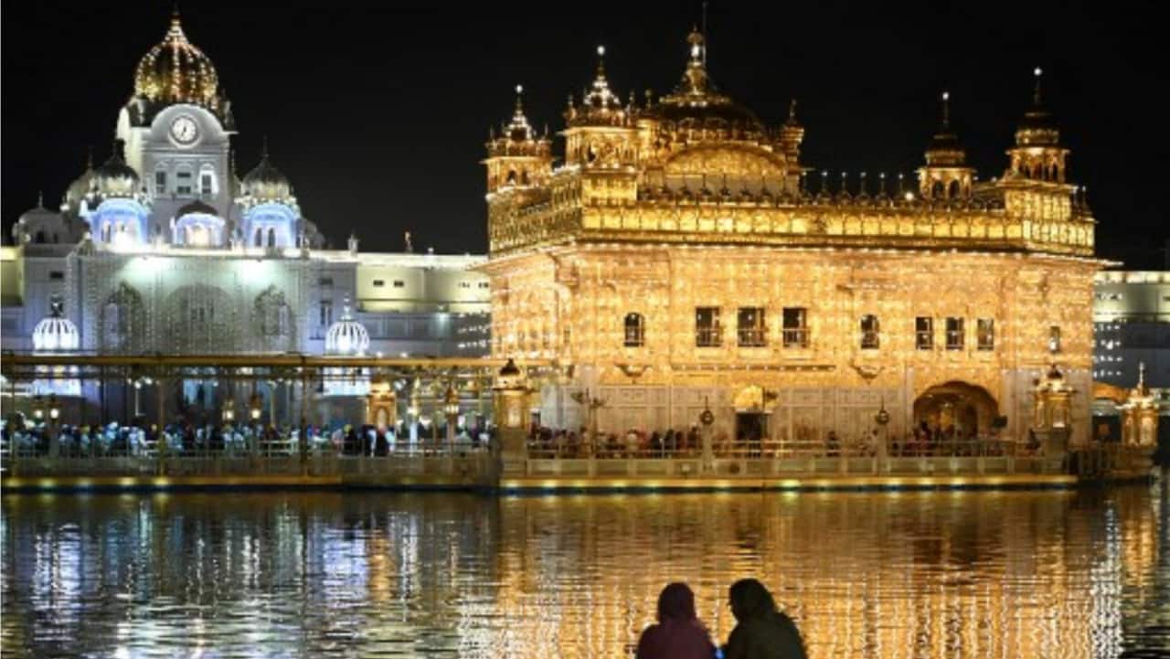 Devotees sit in front of the illuminated Golden Temple on the eve of the birth anniversary of Guru Nanak Dev, the founder of Sikhism, in Amritsar on Tuesday.