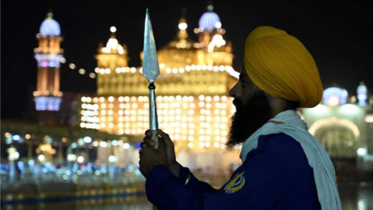 A Sikh volunteer stands guard in front of the illuminated Golden Temple on the eve of the birth anniversary of Guru Nanak Dev, the founder of Sikhism, in Amritsar on Tuesday.