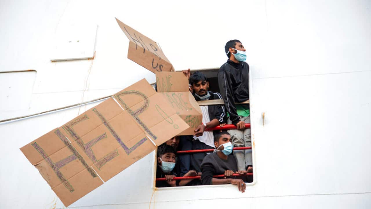 Migrants show placards demanding the disembark for all as the wait aboard of the Norway-flagged Geo Barents rescue ship , in Catania's port, Sicily, southern Italy, Tuesday, Nov. 8, 2022. The Geo Barents, and the German-flagged Humanity1 have been allowed to disembark what the Italian authorities defined &quot;vulnerable people&quot; and minors, while other two ships carrying rescued migrants remained at sea. 