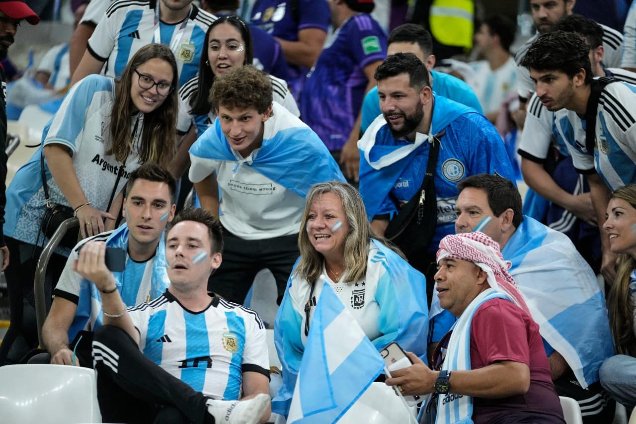 Fans of Argentina watch on a mobile screen the soccer match between Croatia and Brazil prior the start of the World Cup quarterfinal soccer match between the Netherlands and Argentina, at the Lusail Stadium in Lusail, Qatar, Friday, Dec. 9, 2022. (AP Photo/Jorge Saenz)