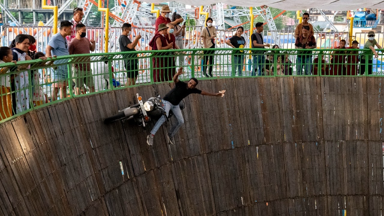 Gulfam Raza sits sideways on his fast moving Royal Enfield motorcycle in an enclosure known as Maut ka Kuan, or the well of death, at a local fair in Dharmsala, India, April 9. (Image: AP)