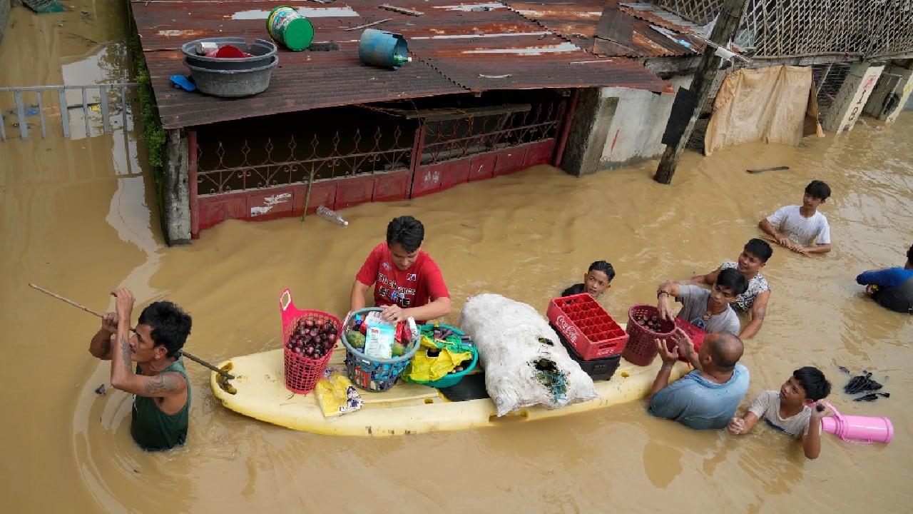 Residents give away onions and other foods along a flooded road due to Typhoon Noru in San Miguel town, Bulacan province, Philippines, September 26. (Image: AP)