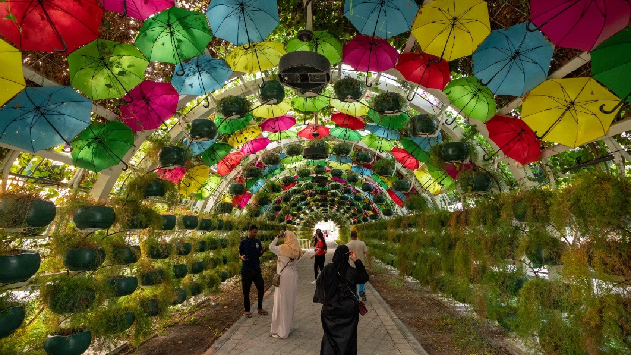 People walk through the floral arch at the Al Masrah Park on Doha corniche, in Doha, Qatar.