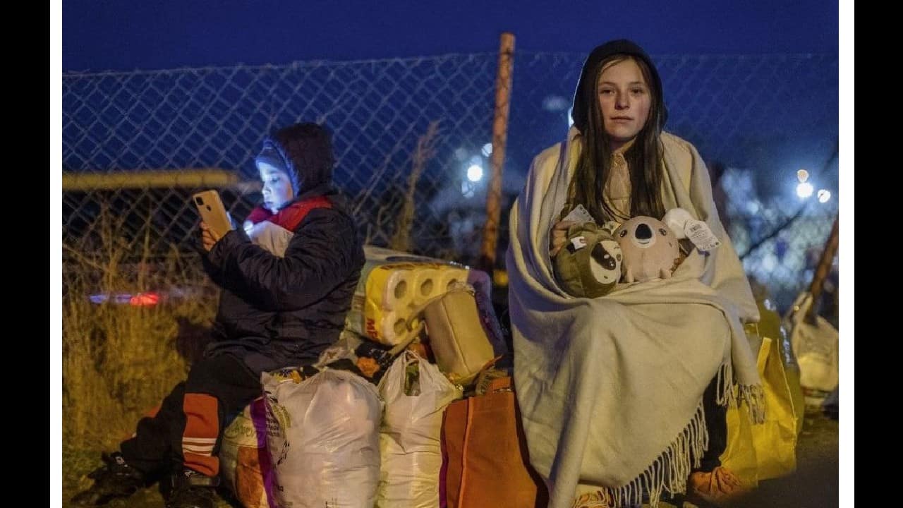 Helena (R) and her brother Bodia (L) from Lviv sit with their belongings at the Medyka pedestrian border crossing, in eastern Poland on February 26, following the Russian invasion of Ukraine. (Image: AFP)