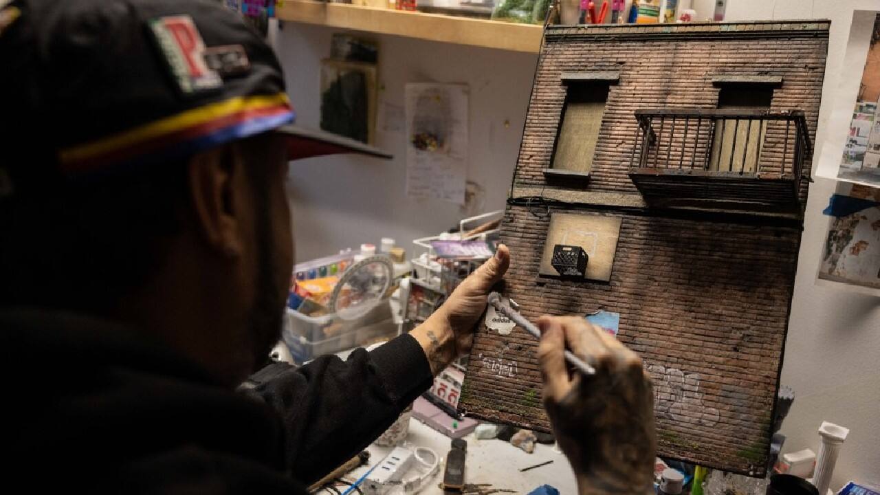 On his table was a current project, the tiny replica of a worn and dirty building facade. Near a bricked-in window, a plastic bushel basket had been hung: a poor man's basketball hoop. &quot;This represents my childhood,&quot; Cortes said, putting touches to the model in his preferred medium, polystyrene. &quot;Everything looked like this: abandoned, empty, a lot of drugs in the area.&quot; (Image: AFP)