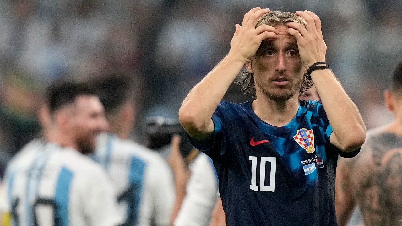 Croatia's Luka Modric reacts, while Argentina's Lionel Messi, background left, celebrates, at the end of the World Cup semifinal soccer match between Argentina and Croatia at the Lusail Stadium in Lusail, Qatar. (Source: AP)