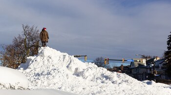 Camille Lockwood stands on a pile of snow on Christmas Day in Buffalo, N.Y., Dec. 25, 2022. The death toll from the violent snowstorm that has blanketed parts of Western New York in nearly four feet of snow rose to seven people overnight. (Jalen Wright/The New York Times)
