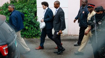 Sam Bankman-Fried, founder of FTX (second left) is escorted out of the Magistrate's Court in Nassau, Bahamas, on Wednesday, Dec. 21, 2022. Bankman-Fried is on his way to an airport to be flown to the US to face a litany of criminal charges after a Bahamas judge approved his extradition. (Photographer: Tristan Wheelock/Bloomberg)