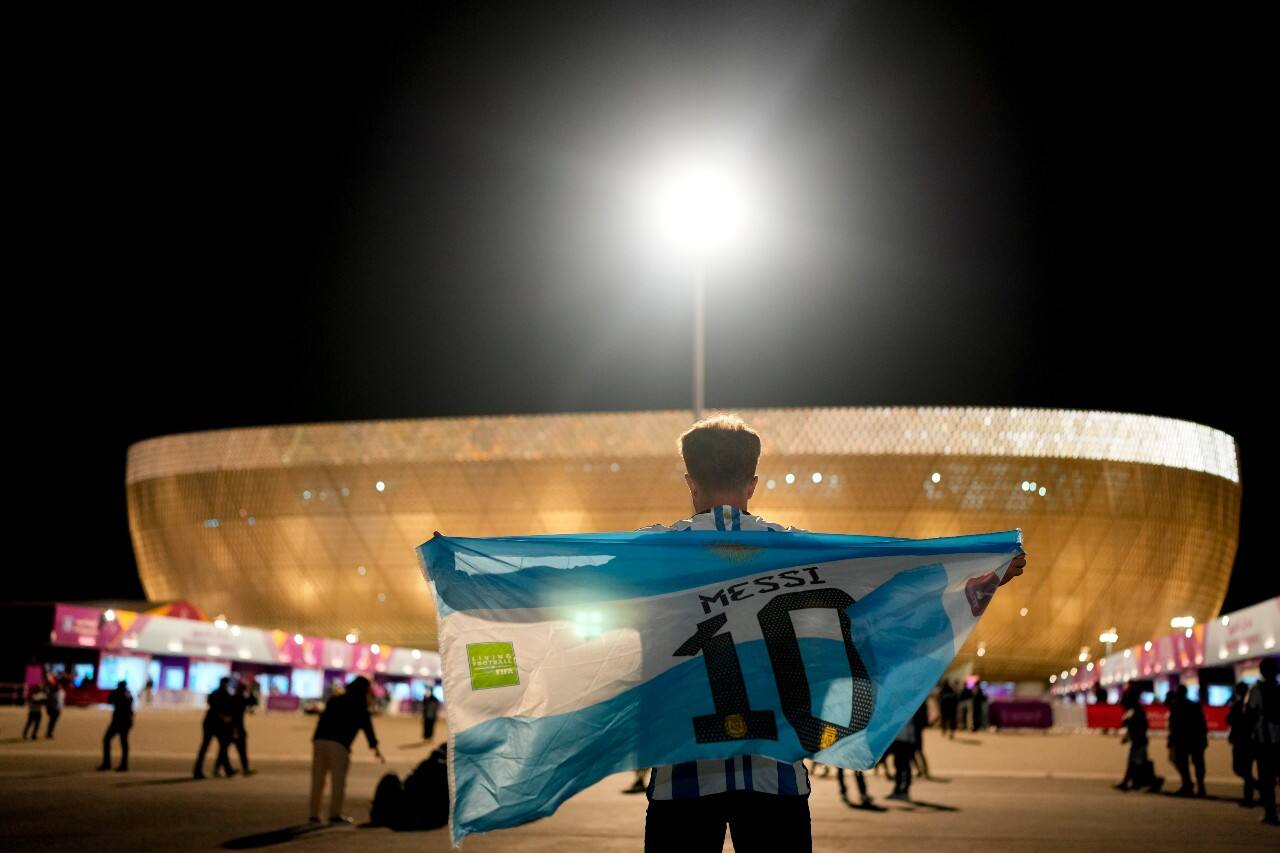 A man holds an Argentinian flag prior to the World Cup quarterfinal soccer match between the Netherlands and Argentina, outside the Lusail Stadium in Lusail, Qatar, Friday, Dec. 9, 2022. (AP Photo/Natacha Pisarenko)
