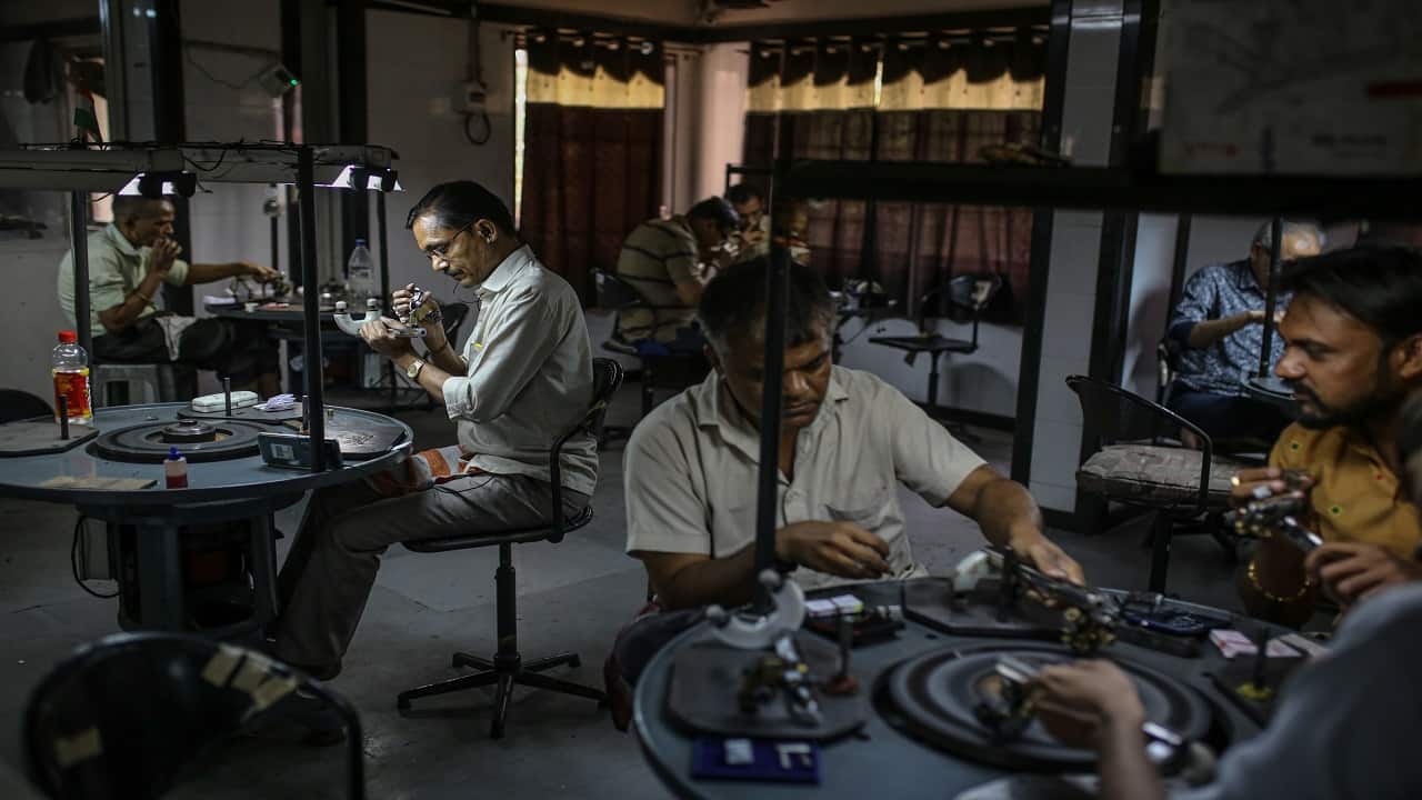 Employees inspect and polish diamonds at a workshop in Surat, Gujarat, India.