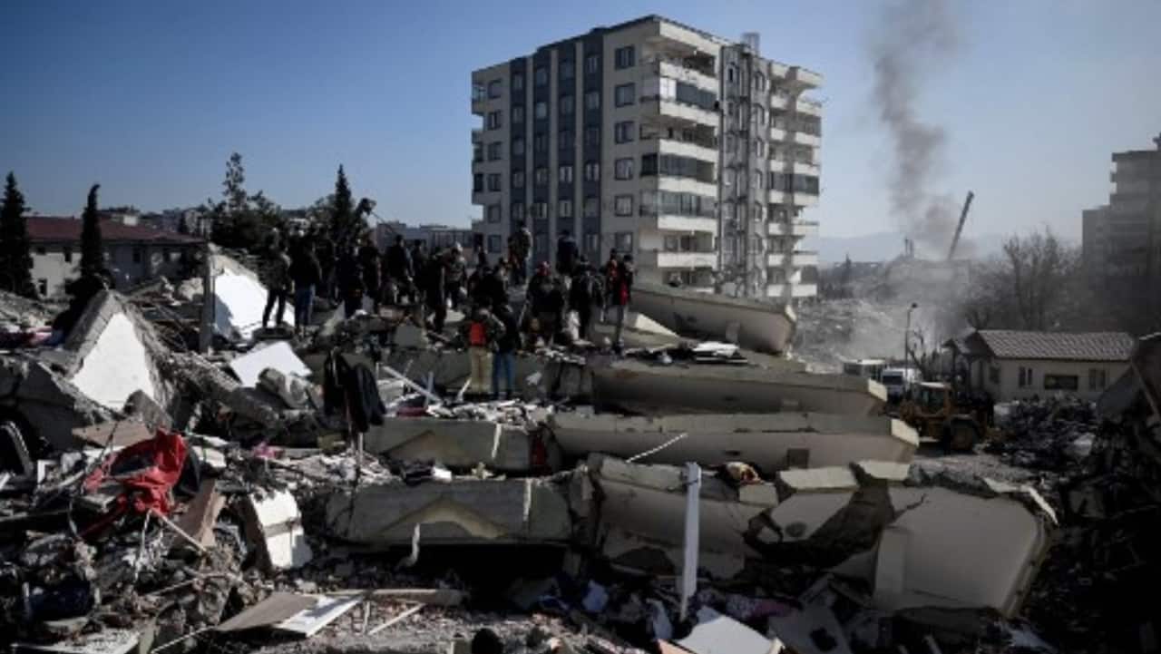 People wait as rescuers carry out search operations among the rubble of collapsed buildings in Kahramanmaras, on February 9, 2023, three days after a 7,8-magnitude earthquake struck southeast Turkey. 
