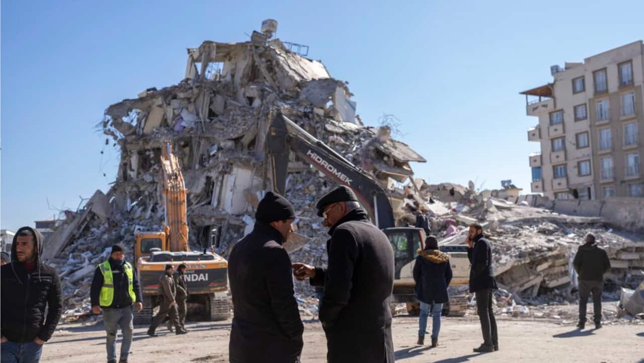 Local residents stand in front of a destroyed building in Nurdagi, southeastern Turkey, Thursday.