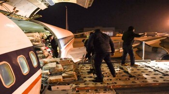 Workers unload aid sent by Iran by plane, at the airport in Syria's northern city of Aleppo early on February 8, 2023, following a deadly earthquake. (AFP)