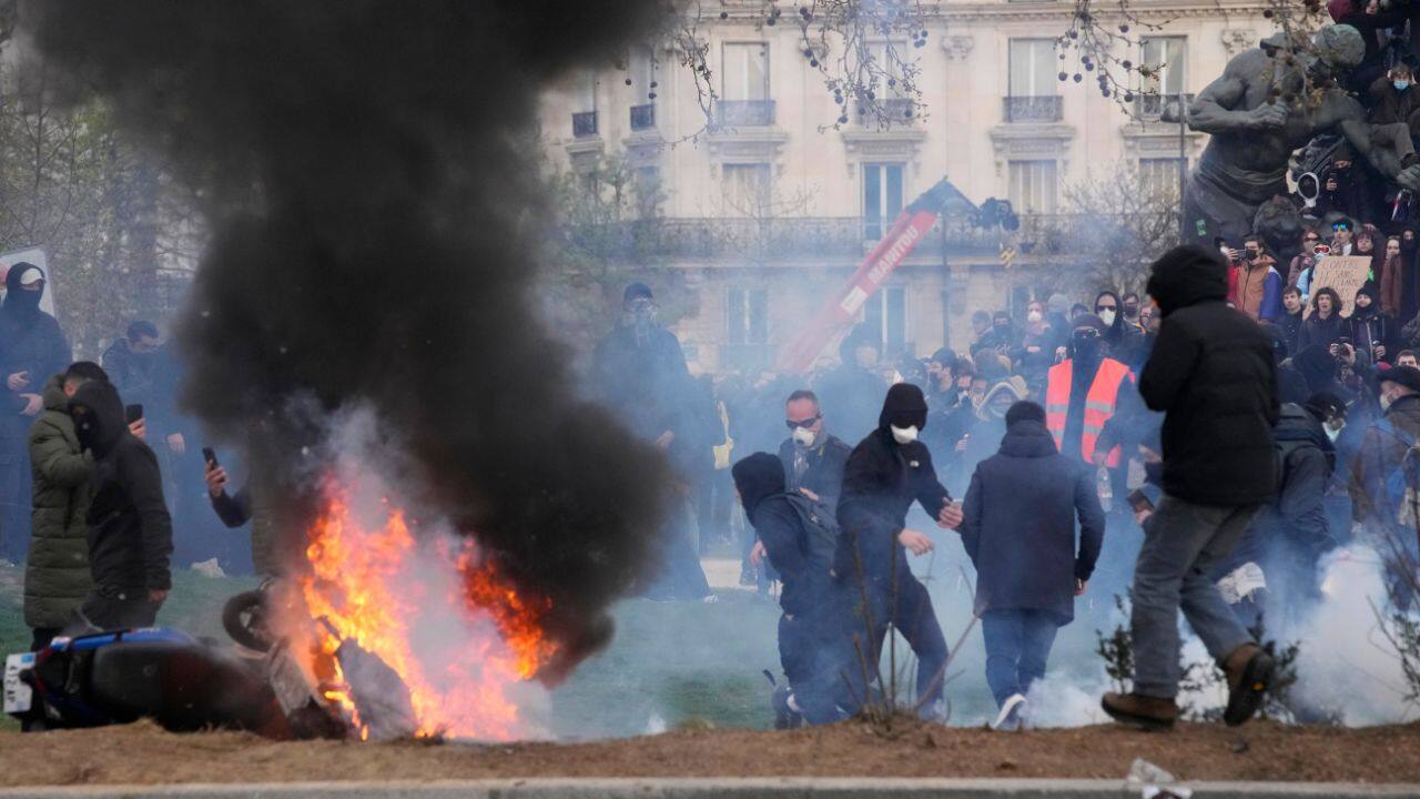 A group of security forces in Paris at one point withdrew behind the wooden doors of a residential building during hours-long standoffs against ultra-leftist militants attacking with various projectiles and fireworks. A fire raged outside the door. (Source: AP)