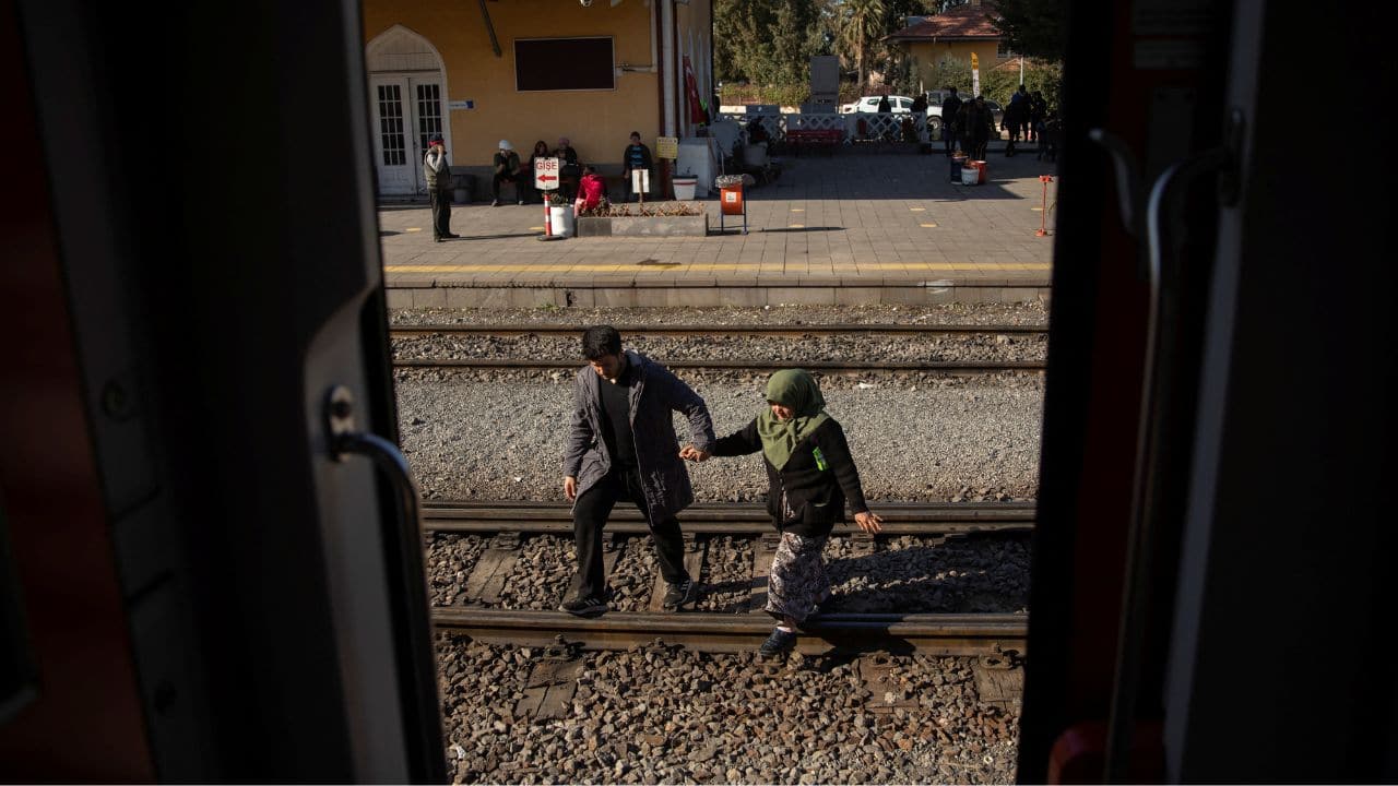 A man and a woman cross the tracks at Iskenderun train station, where carriages have been turned into temporary shelters for victims of the recent deadly earthquake, in Iskenderun, Turkey, February 15. (Source: Reuters)