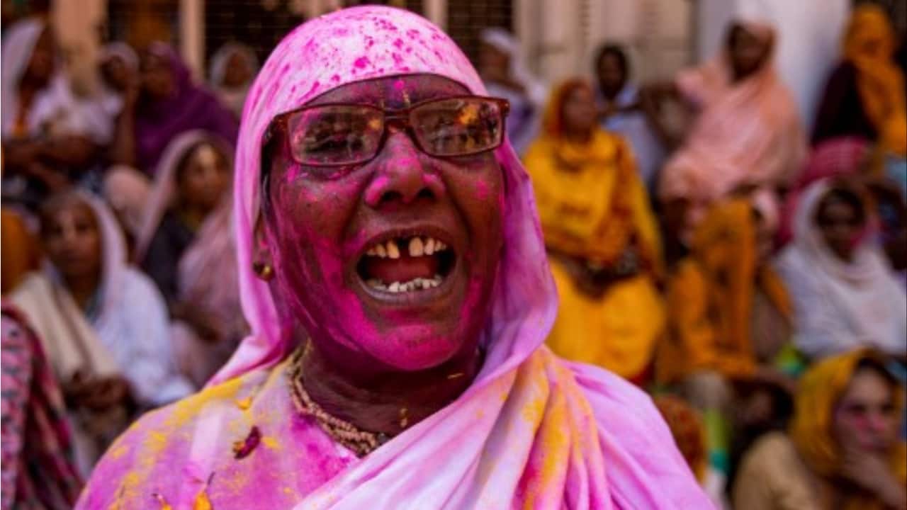 A widow, daubed in 'Gulal' celebrates Holi at a temple, in Vrindavan.