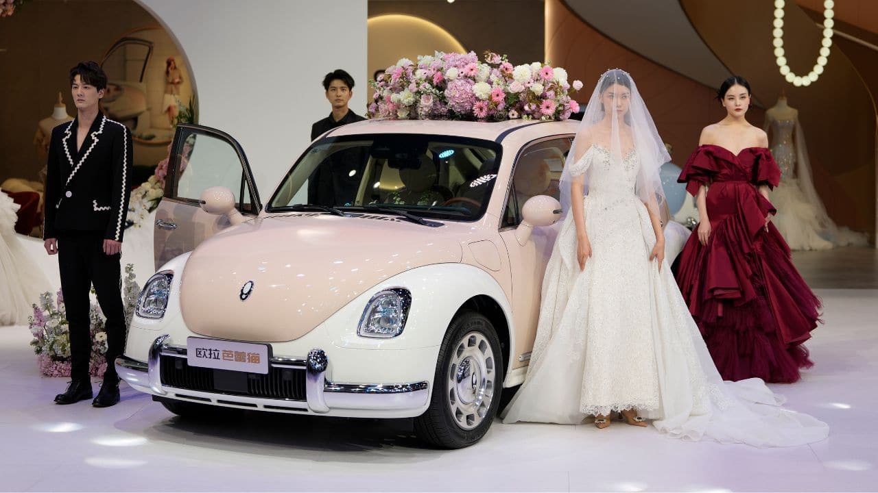 Models in wedding gowns showcase the Ora Funky Cat EV car model by Great Wall Motor during the Auto Shanghai 2023 at the National Exhibition and Convention Center in Shanghai, China. (Image: AP)