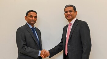 K Krithivasan and Rajesh Gopinathan shaking hands, looking at the camera