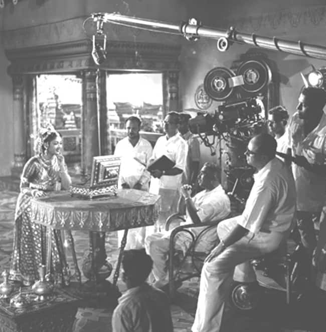 Production still of Mayabazar (1957) where Savitri enacts a scene with Priya darsini mirror; also seen in the picture are director K.V. Reddy and cinematographer Marcus Bartley Date1956