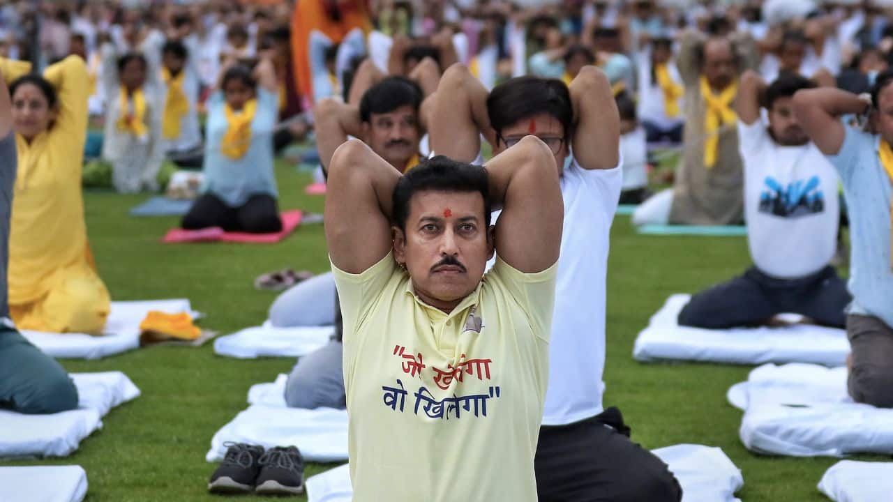 BJP MP Rajyavardhan Singh Rathore with others performs yoga on the International Day of Yoga, at the Maharana Pratap Sports College, in Jaipur. (Image: PTI)