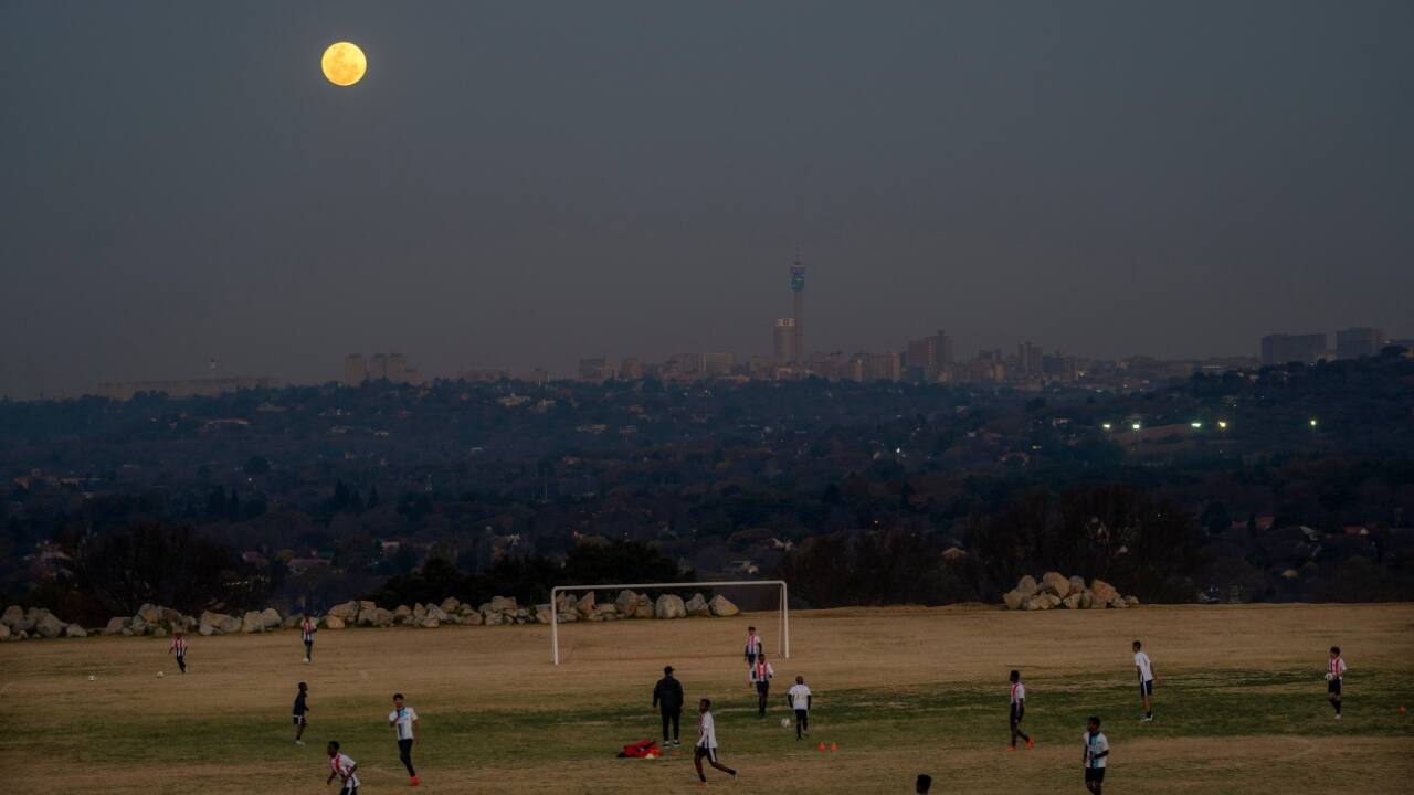 With the city of Johannesburg and a rising supermoon in the background, young football players practice in Johannesburg, South Africa. (Image: AP)