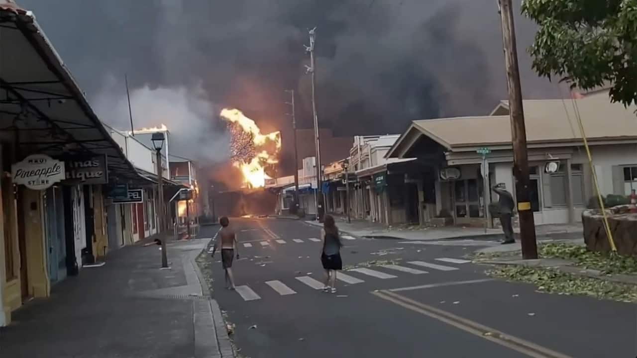 Spectators gaze upon billowing smoke and flames engulfing downtown Lahaina's Front Street, Maui, on Tuesday, August 8, 2023. In a significant blow to tourism, raging wildfires have ravaged portions of this iconic Hawaiian tourist hub. County of Maui spokesperson Mahina Martin, in an early Wednesday phone interview, confirmed the extensive reach of the fire, encompassing the favored tourist hotspot of Front Street in Lahaina. (Image: AP)
