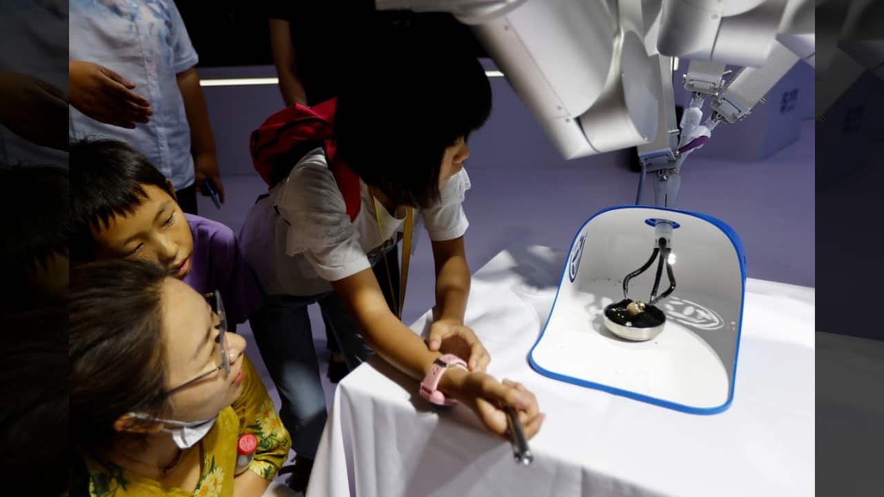 Visitors look at a single-port surgical robot developed by Shurui peeling a quail egg, at the Beijing World Robot Conference (WRC) 2023 in Beijing, China, August 17. (Image: Reuters)