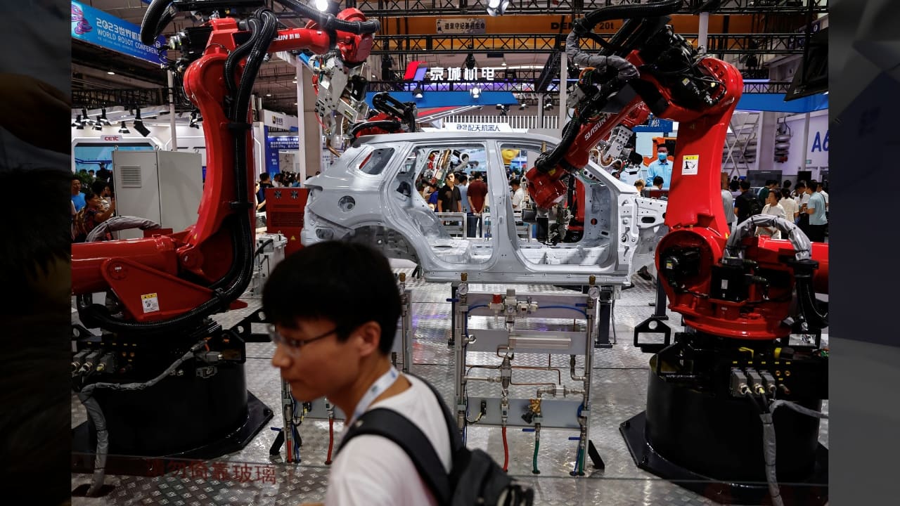 A visitor stands near robotic welding arms used in car production developed by Siasun, at the Beijing World Robot Conference (WRC) 2023 in Beijing, China, August 17. (Image: Reuters)