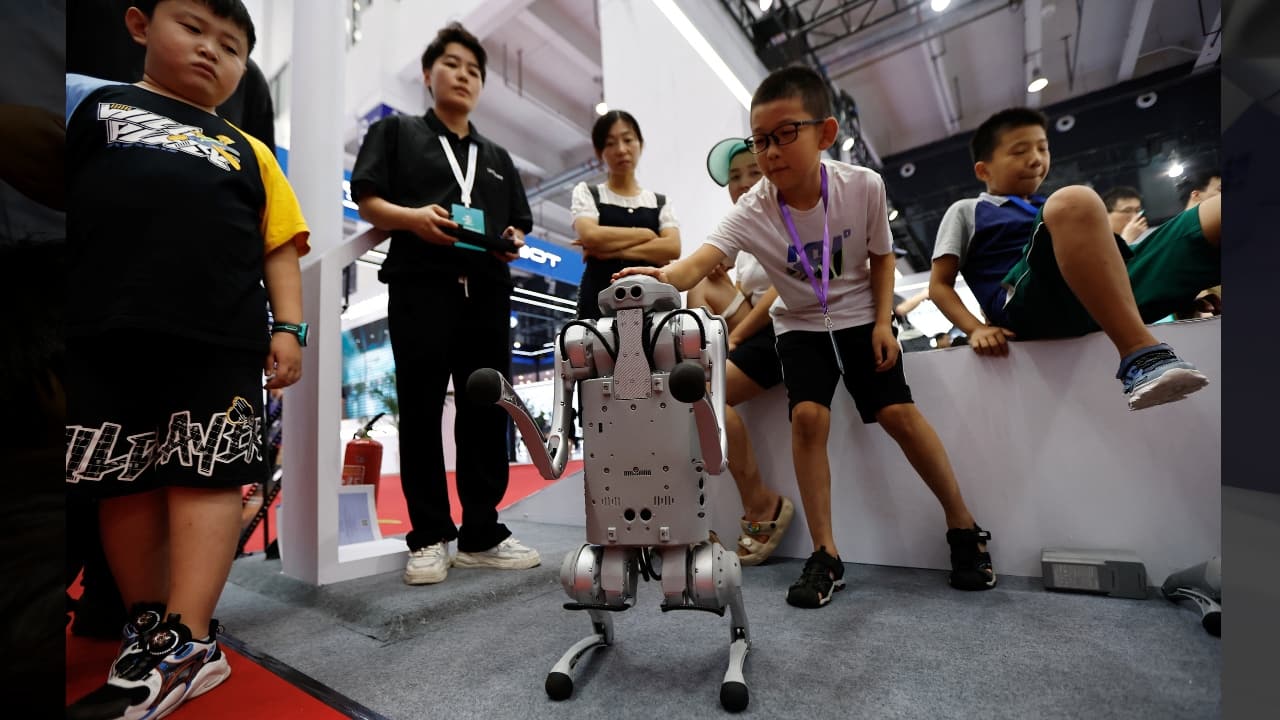 A kid pats a robot dog by Unitree at the Beijing World Robot Conference (WRC) 2023 in Beijing, China, August 17. (Image: Reuters)
