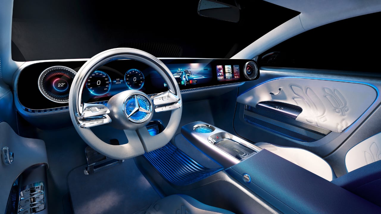 Inside the Concept CLA Class, a full-width MBUX Superscreen, similar to that of the Vision EQXX, takes center stage. It runs on Mercedes-Benz's new MB.OS operating system and enhances the tech-oriented aesthetics of the cabin. The Superscreen includes turbine-like virtual air vents with physical control interfaces and a floating center armrest with a wireless charger and cupholder. Sustainable nappa leather, ambient lighting, and innovative controls contribute to the interior's premium feel. (Image: Mercedes Benz)