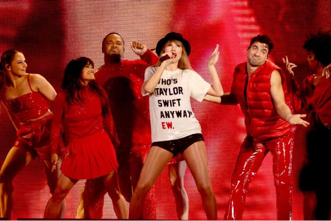 Taylor Swift wearing a T-shirt that reads 'Who is Taylor Swift anyway, ew'.