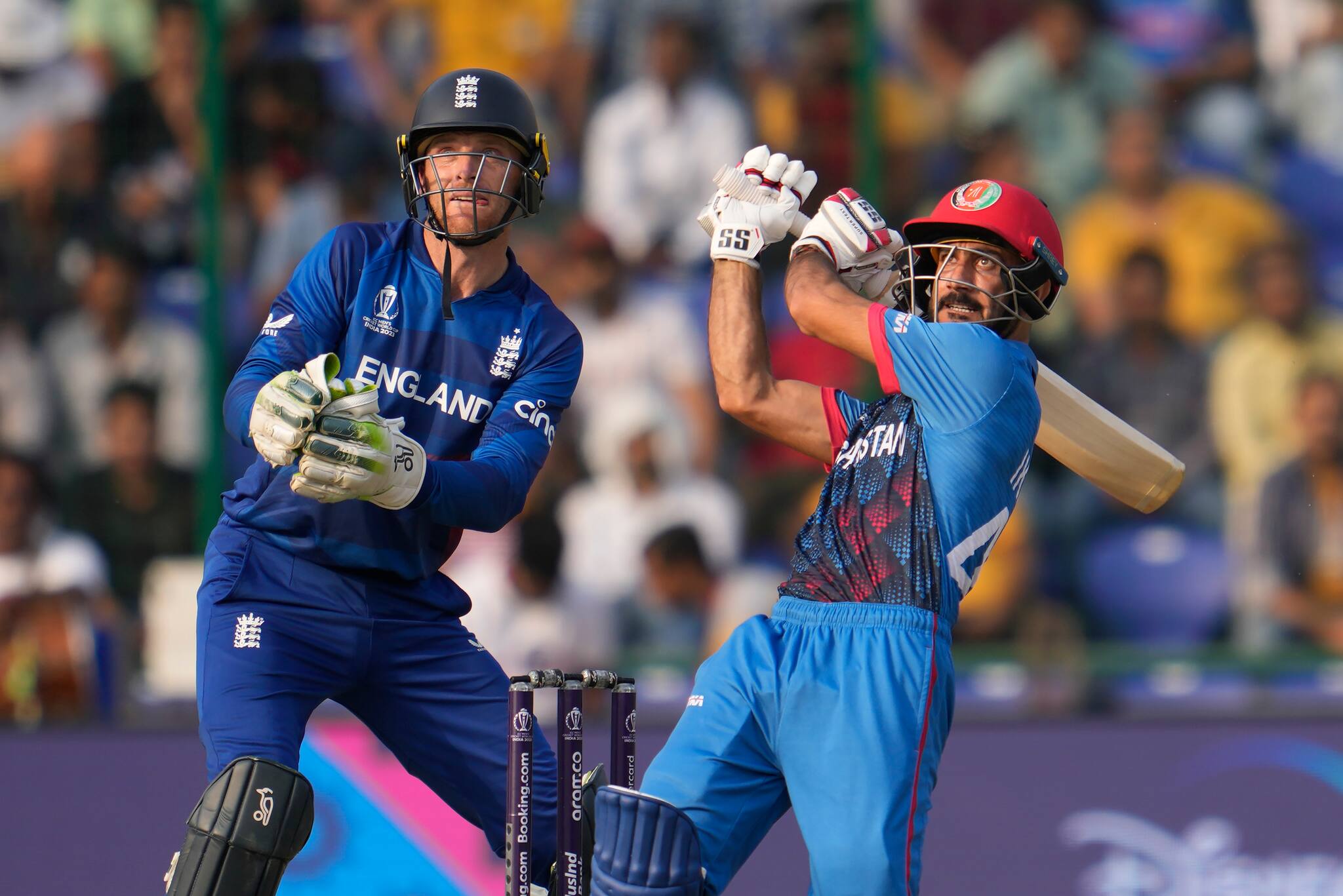 Afghanistan's Ikram Alikhil hits a six as England's captain Jos Butler watches during the ICC Men's Cricket World Cup match between Afghanistan and England in New Delhi, India, Sunday, Oct. 15, 2023. (AP Photo/Manish Swarup)