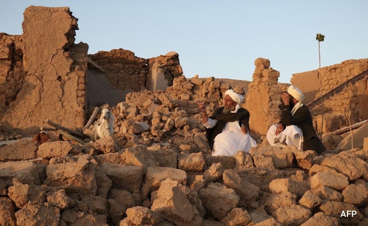Afghans stand in what used to be a courtyard of their destroyed homes. [Omid Haqjoo/AP Photo]