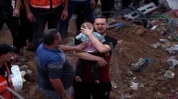 A Palestinian man cries while holding a baby affected by an Israeli air strike in the al-Nuseirat refugee camp in the central Gaza Strip on October 31. (Image: AP)