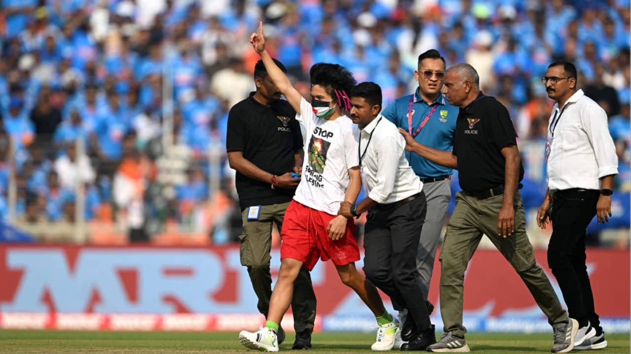 A pitch invader is taken off the field by security personnel during the 2023 ICC Men's Cricket World Cup one-day international (ODI) final match between India and Australia at the Narendra Modi Stadium in Ahmedabad on November 19. (Image credit: AFP)