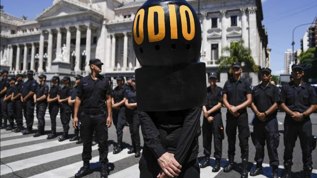 A demonstrator wearing the Spanish word “Hate” stands in front of police standing guard outside Congress in Buenos Aires, Argentina, Wednesday, Jan. 24, 2024. (AP Photo/Rodrigo Abd)