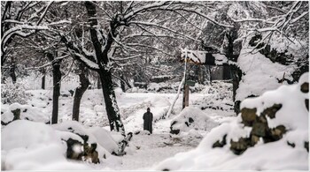 A man walks through a field covered in fresh snow on the outskirts of Srinagar. (Image credit: AP)