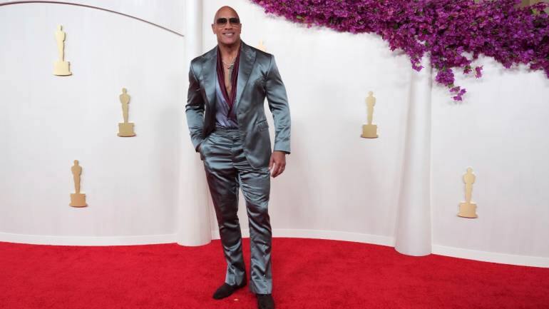 Dwayne &quot;The Rock&quot; Johnson sported a silk slate three-piece suit with a burgundy silk scarf, showcasing his impeccable style (Image: AP)