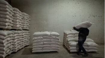 A worker carries a bag of animal feed at the Union of Agricultural Cooperatives on the island of Naxos, Greece