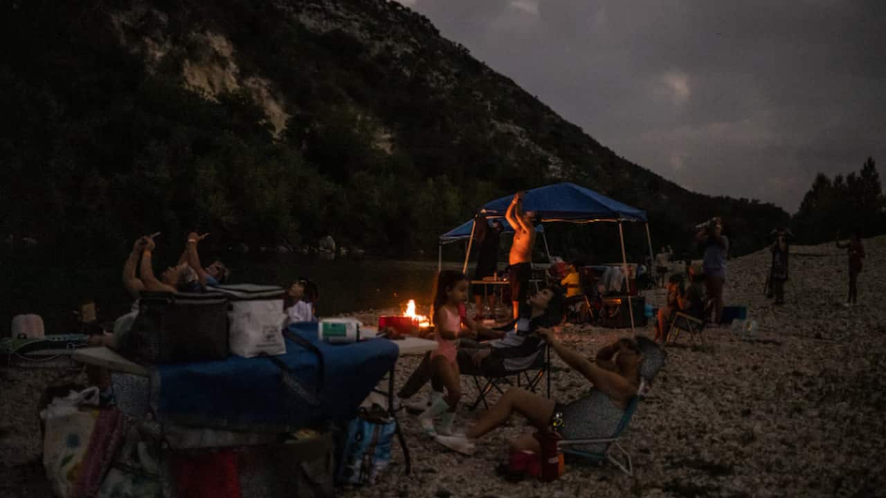 Anthony Longoria, of Atascosa, Texas, is lit by a fire while observing the peak totality of the solar eclipse next to the Nueces River at Chalk Bluff, in Uvalde, Texas. REUTERS/Adrees Latif