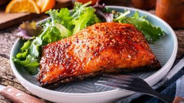 Salmon: Rich in omega-3 fatty acids, salmon can help reduce inflammation and improve brain function, which can positively impact mood. Omega-3s are also important for overall brain health. (Image: Canva)