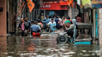 People wade through a waterlogged road near Sarai Kale Khan area after rain, in New Delhi (PTI Photo)
