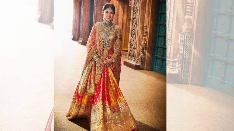 According to the designer, her vidaai outfit was a testament to 19th-century Indian craftsmanship, seamlessly woven into modern bridal fashion. The crimson-orange sunset hued lehenga was crafted from luxurious Banarasi brocade, exuding a rich, opulent texture that is synonymous with traditional Indian bridal wear. Paired with the lehenga was an imperial red satin blouse, featuring intricate gold karchobi inspired by Kutch’s heritage. The blouse was detailed with zari and badla, creating a striking interplay of tradition and modernity (Image: @manishmalhotraworld, @manishmalhotravows/Instagram)