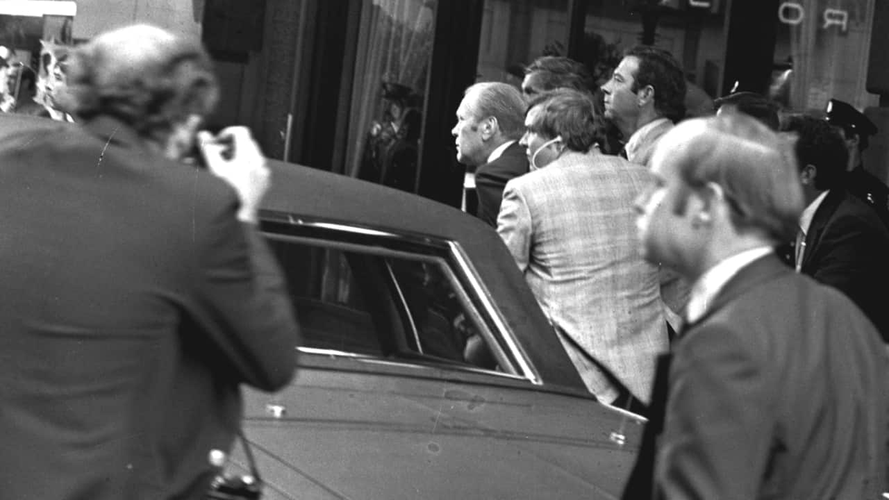 President Ford ducks behind his limousine and is hustled into the vehicle after a shot was fired as he left the St. Francis Hotel in San Francisco, Sept. 22, The President was rushed to the airport to return to Washington.