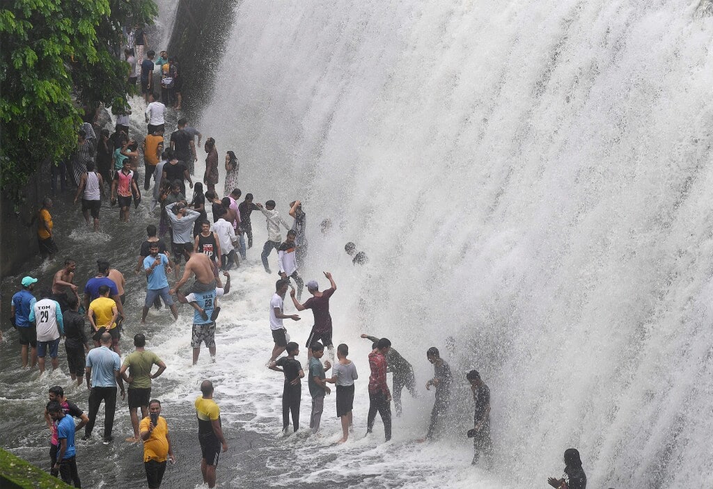 People play in water from the overflowing Powai lake following heavy rainfall, in Mumbai, Sunday, July 14, 2024. (PTI Photo)