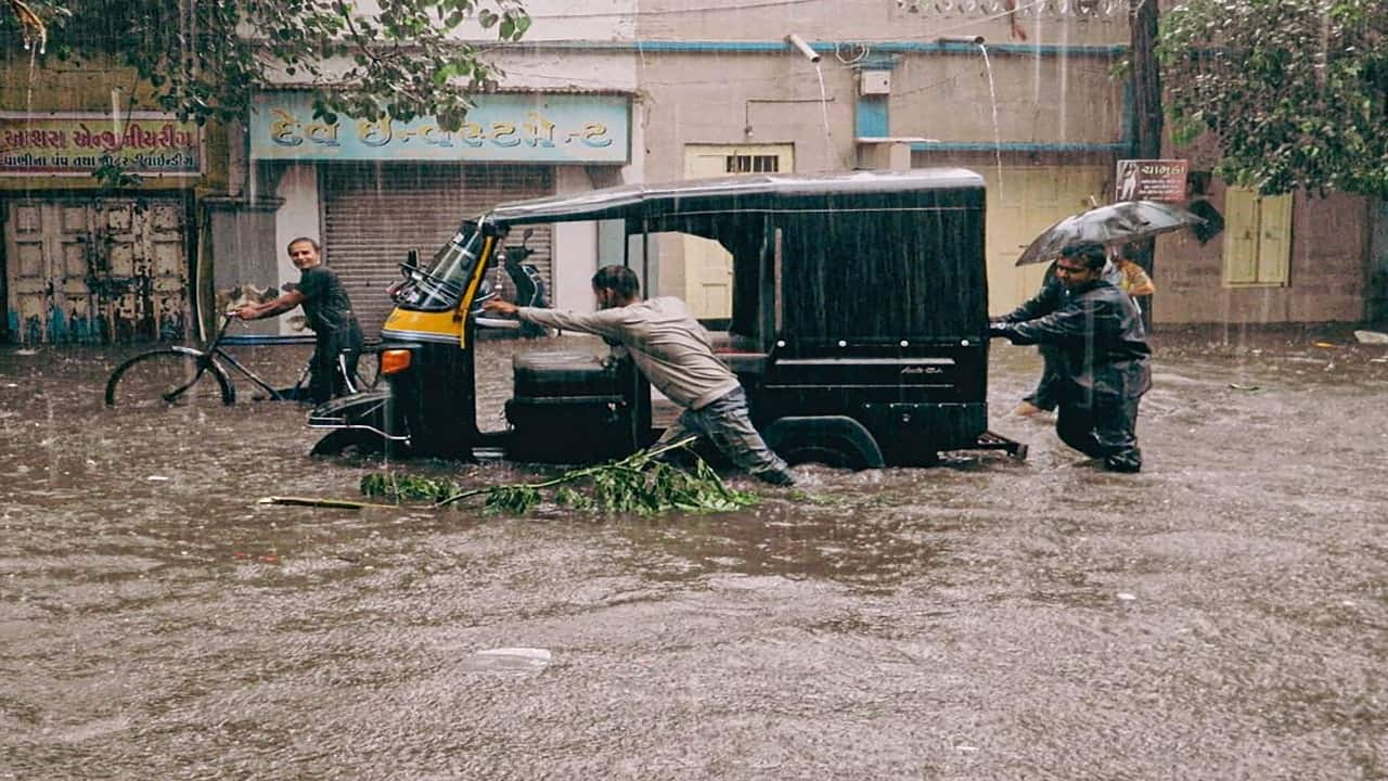 A rickshaw driver pushes his vehicle through waterlogged streets after a heavy downpour in Mumbai. (File photo)