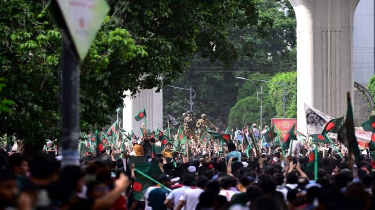 Protesters march towards Sheikh Hasina's palace as army personnel stand guard in the Shahbag area, near Dhaka University, on August 5. What began as student-led demonstrations against government hiring rules in July escalated, leading to Hasina fleeing the country and the military announcing plans to form an interim government. Protesters march towards Sheikh Hasina's palace as army personnel stand guard in the Shahbag area, near Dhaka University, on August 5. What began as student-led demonstrations against government hiring rules in July escalated, leading to Hasina fleeing the country and the military announcing plans to form an interim government.