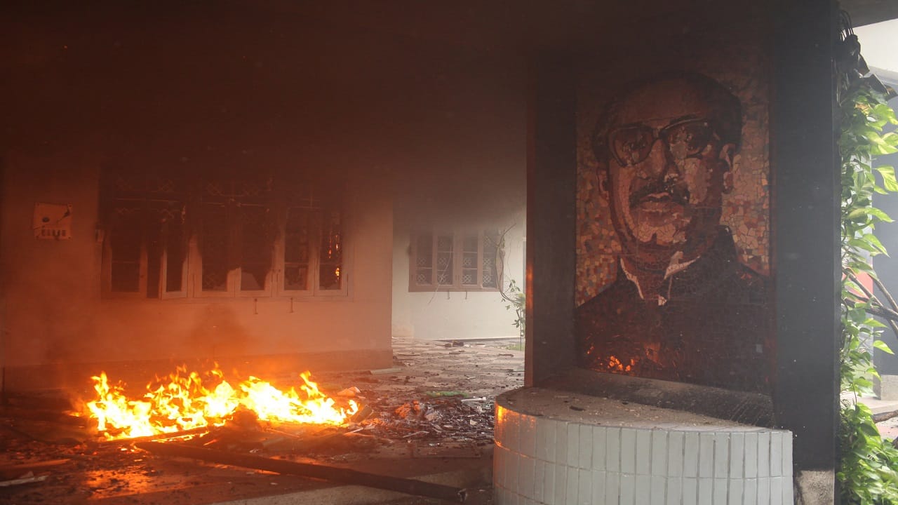 A portrait of Bangladesh's founding father, Sheikh Mujibur Rahman, is visible as agitators set ablaze the Bangabandhu Memorial Museum in Dhaka on August 5. A portrait of Bangladesh's founding father, Sheikh Mujibur Rahman, is visible as agitators set ablaze the Bangabandhu Memorial Museum in Dhaka on August 5.